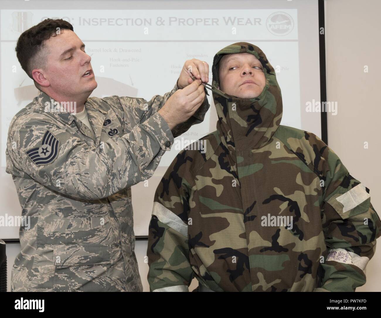 Tech Sgt. Donovan Root (let), 60th Civil Engineer Squadron, demonstrates on Tech. Sgt. Stephen Wentz (right), 9th Air Refueling Squadron, how to secure the hood of a mission-oriented protective posture jacket during a chemical, biological, radiological and nuclear defense survival skills training course on Travis Air Force Base, Calif., Sep. 21, 2017. CBRN defenses are protective measures taken in situations in which chemical, biological, radiological or nuclear warfare (including terrorism) hazards may be present. CBRN defense consists of CBRN passive protection, contamination avoidance and C Stock Photo