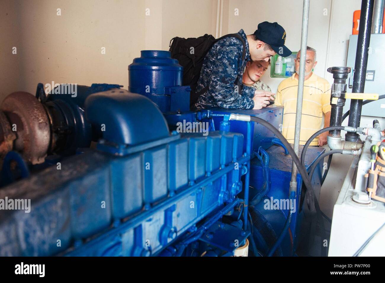 PUERTO RICO (Sept. 26, 2017) - Construction Electrician 3rd Class Joshua Reding, assigned to Construction Battalion Maintenance Unit 202, center, and Machinist Mate 3rd Class Bradley Colon, assigned to the amphibious assault ship USS Kearsarge (LHD 3), left, inspect a generator at the Metropolitano De La Montana Hospital in Puerto Rico. The Department of Defense is supporting the Federal Emergency Management Agency, the lead federal agency, in helping those affected by Hurricane Maria to minimize suffering and as one component of the overall whole-of-government response efforts. Stock Photo