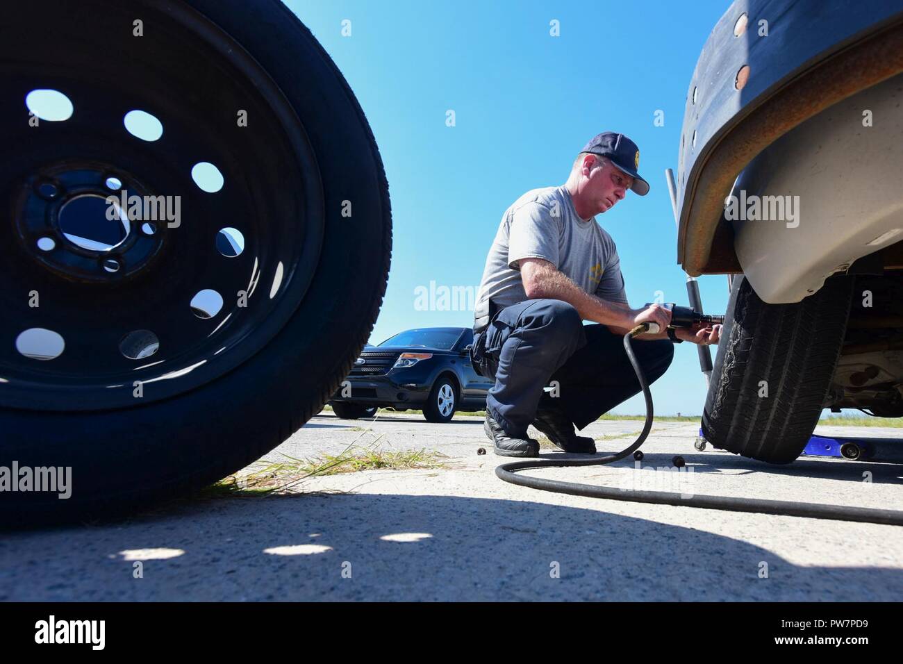 Cpl. Tim Bush, an instructor with the South Carolina Highway Patrol Training Unit, changes a tire on a car during Precision Immobilization Technique training at McEntire Joint National Guard Base, S.C., Sept. 27, 2017. McEntire JNGB, home to the South Carolina Air National Guard’s 169th Fighter Wing, partners with local law enforcement allowing them to utilize sections of the base for necessary training, enhancing the partnership between the SCANG and the S.C. Highway Patrol. Stock Photo
