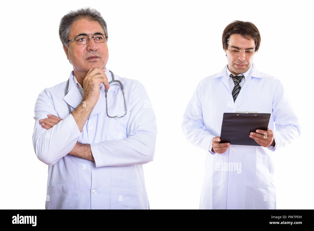 Studio shot of senior Persian man doctor thinking with young Per Stock Photo