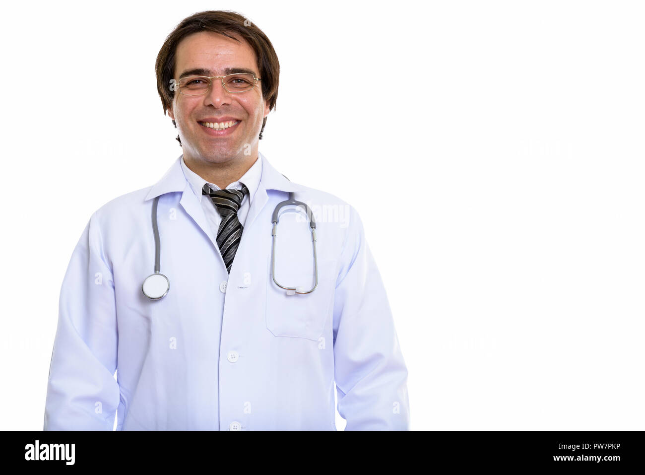 Studio shot of young happy Persian man doctor smiling while wear Stock Photo