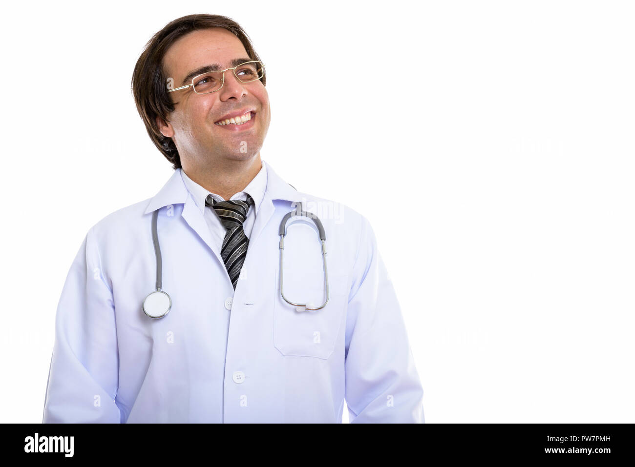 Studio shot of young happy Persian man doctor smiling while thin Stock Photo