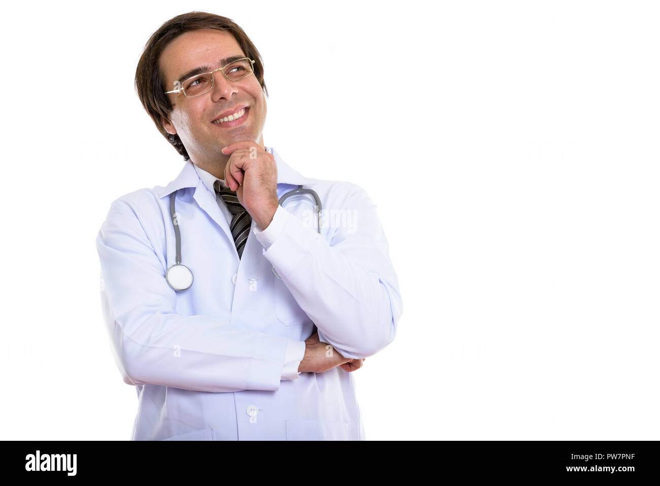 Studio shot of young happy Persian man doctor smiling and thinki Stock Photo