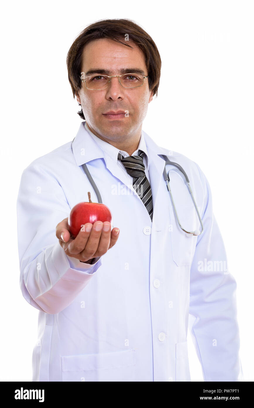 Studio shot of young Persian man doctor giving red apple Stock Photo
