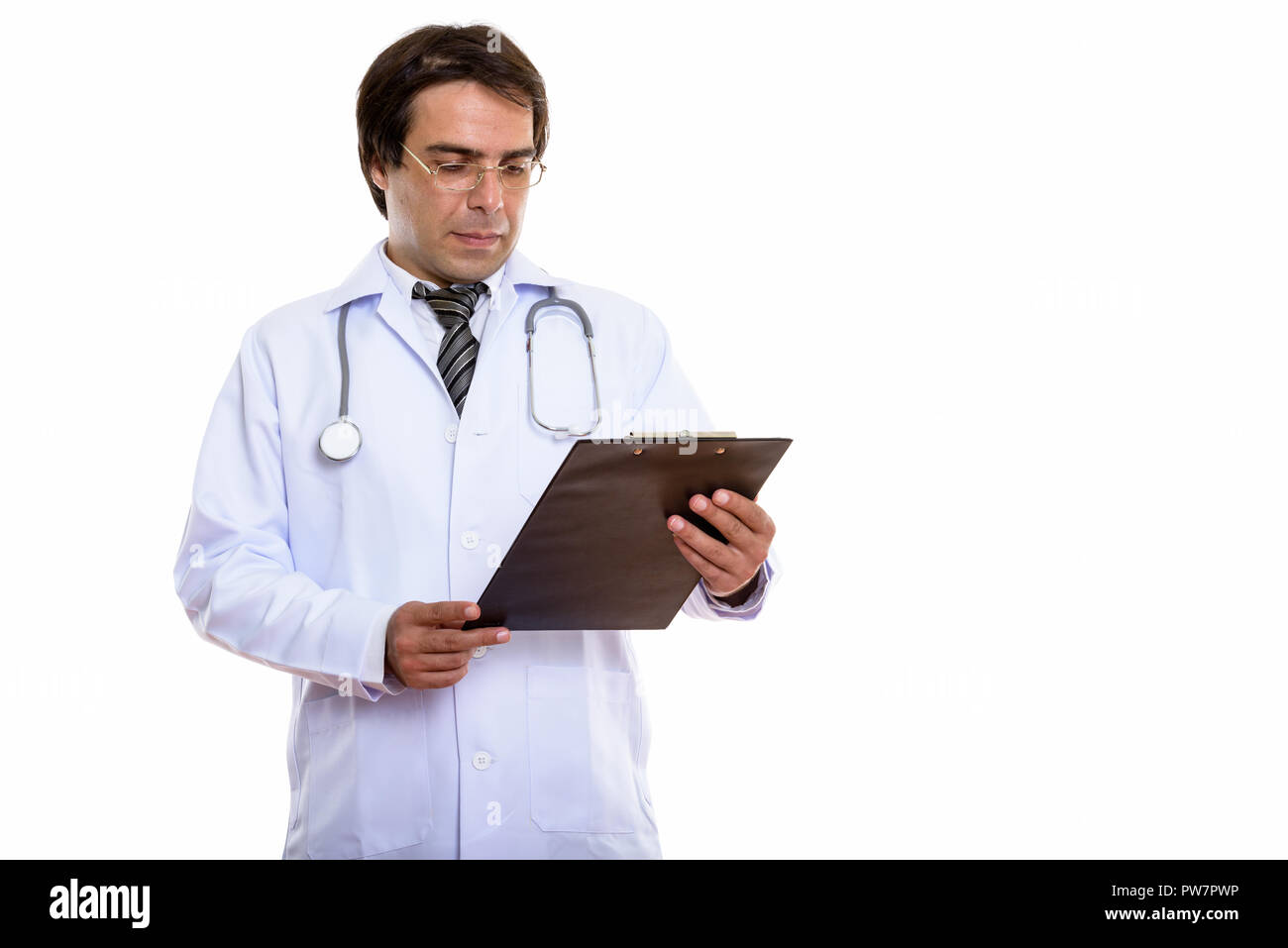 Studio shot of young Persian man doctor reading on clipboard Stock Photo