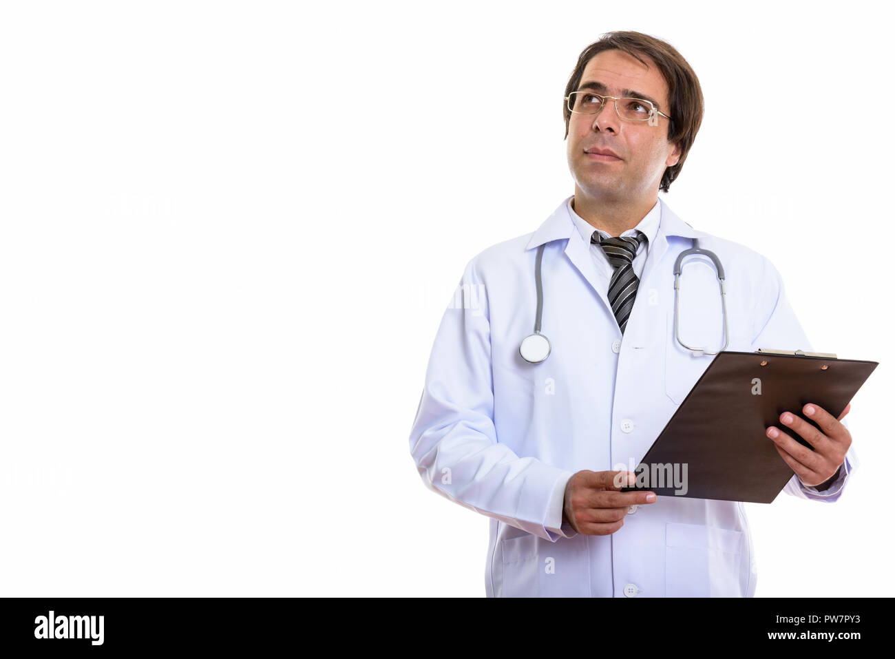 Studio shot of young Persian man doctor holding clipboard while  Stock Photo