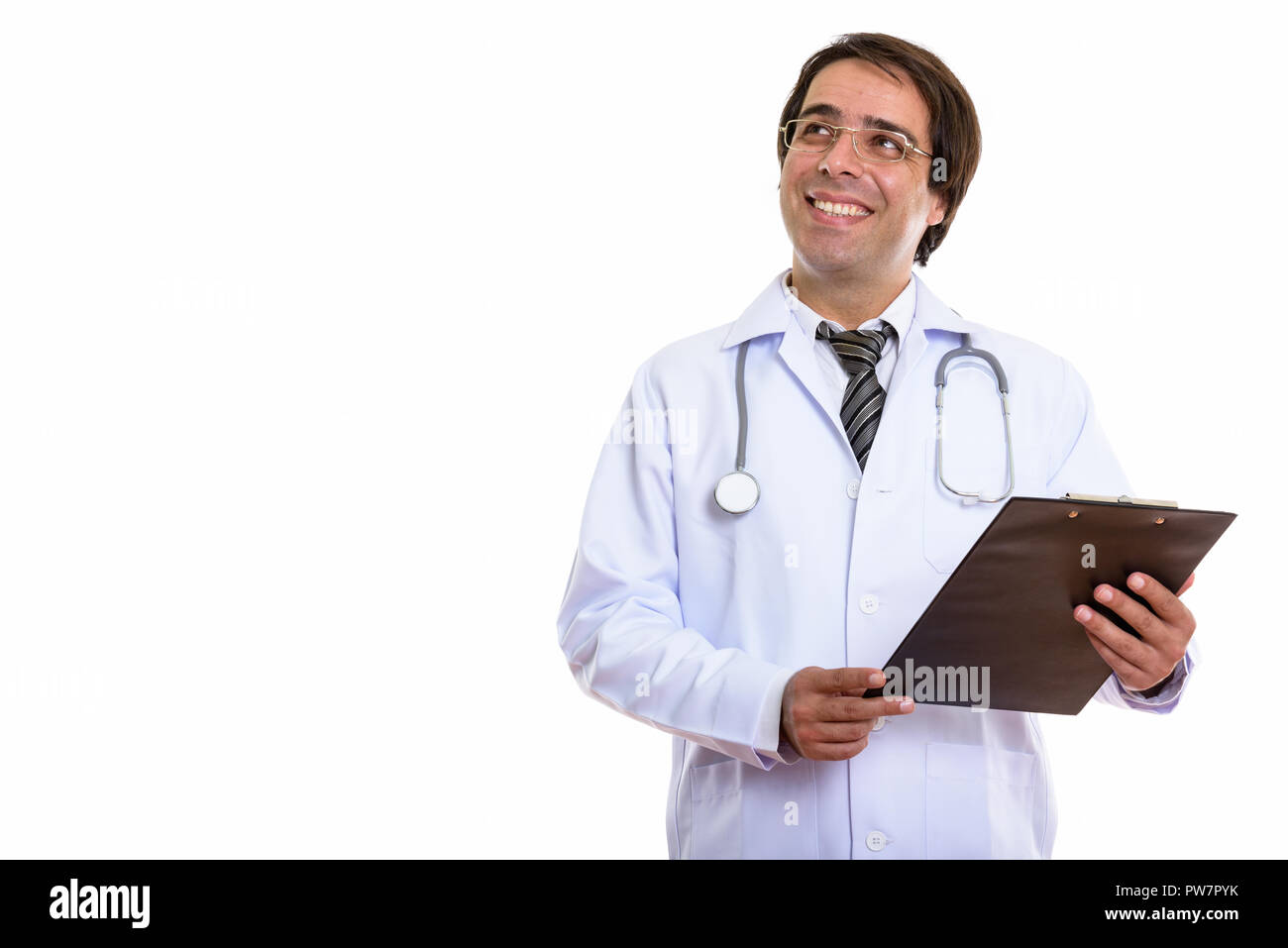 Studio shot of young happy Persian man doctor smiling while hold Stock Photo