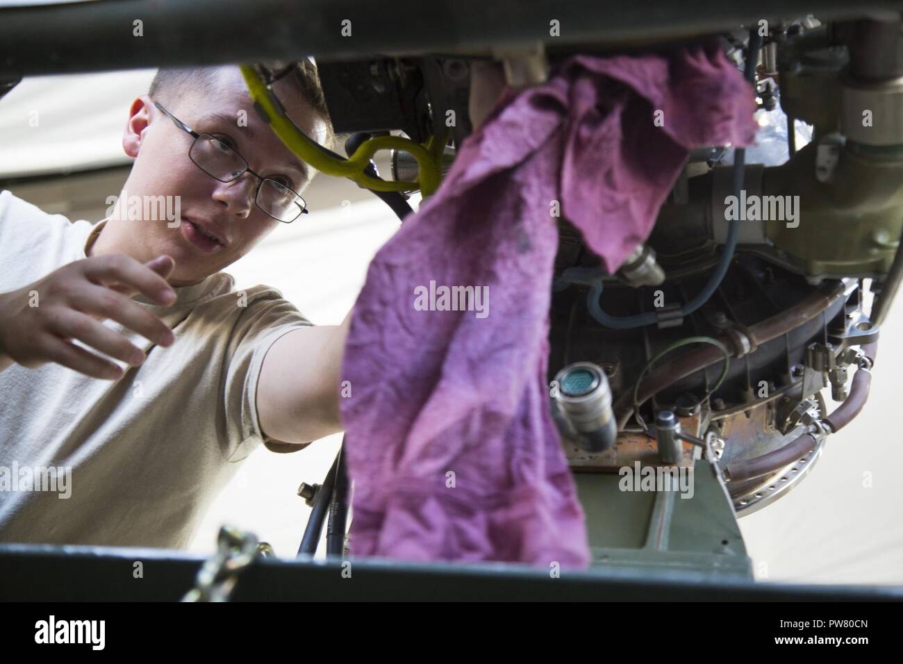 U.S. Army Cpl. Dylan White, deployed in support of Combined Joint Task Force - Operation Inherent Resolve and assigned to 2nd Squadron, 17th Cavalry Regiment, 101st Combat Aviation Brigade, 101st Airborne Division, conducts maintenance on an engine of an AH-64E Apache helicopter at Camp Taji, Oct. 02, 2017. Camp Taji is one of four CJTF - OIR building partner capacity locations dedicated to training partner forces and enhancing their effectiveness on the battlefield. CJTF - OIR is the global Coalition to defeat ISIS in Iraq and Syria. Stock Photo