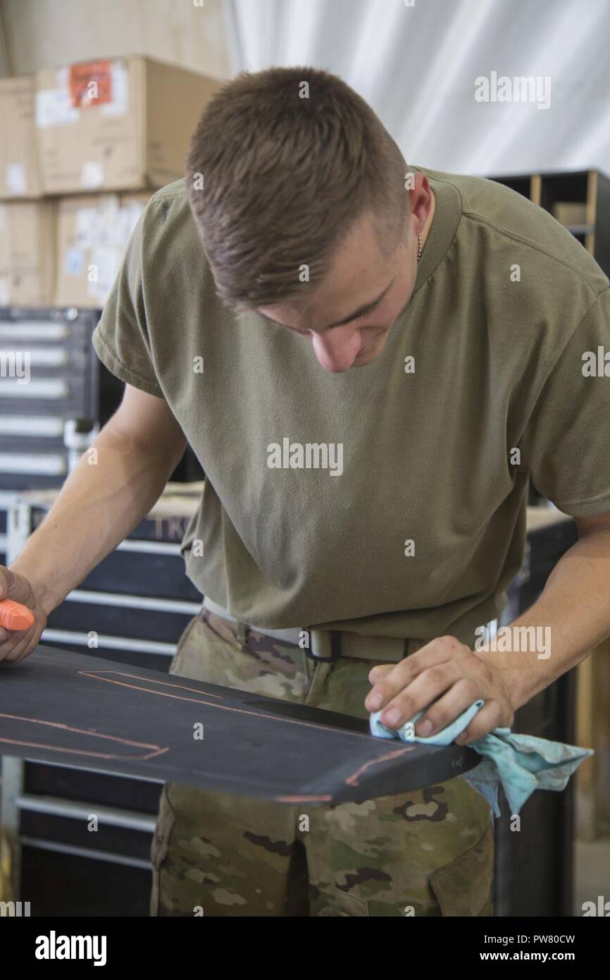 U.S. Army Spc. James Stewart, deployed in support of Combined Joint Task Force - Operation Inherent Resolve and assigned to 2nd Squadron, 17th Cavalry Regiment, 101st Combat Aviation Brigade, 101st Airborne Division, marks in chalk damages on the propellers of an AH-64E Apache helicopter at Camp Taji, Oct. 02, 2017. Camp Taji is one of four CJTF - OIR building partner capacity locations dedicated to training partner forces and enhancing their effectiveness on the battlefield. CJTF - OIR is the global Coalition to defeat ISIS in Iraq and Syria. Stock Photo