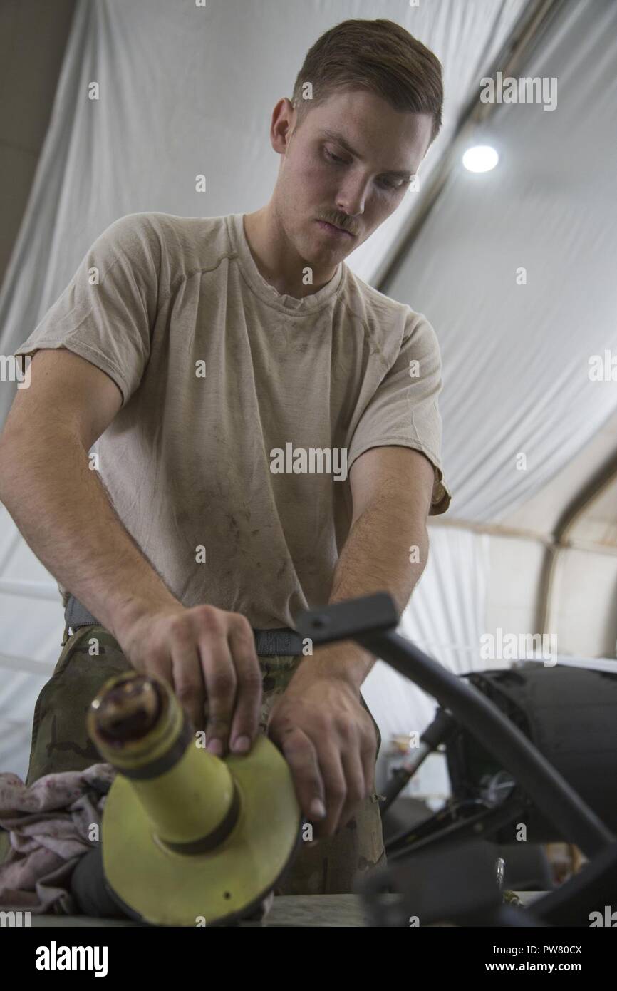 U.S. Army Spc. Ryan Kennedy, deployed in support of Combined Joint Task Force - Operation Inherent Resolve and assigned to 2nd Squadron, 17th Cavalry Regiment, 101st Combat Aviation Brigade, 101st Airborne Division, conducts maintenance on the rear landing gear of an AH-64E Apache helicopter at Camp Taji, Oct. 02, 2017. Camp Taji is one of four  CJTF - OIR building partner capacity locations dedicated to training partner forces and enhancing their effectiveness on the battlefield. CJTF - OIR is the global Coalition to defeat ISIS in Iraq and Syria. Stock Photo