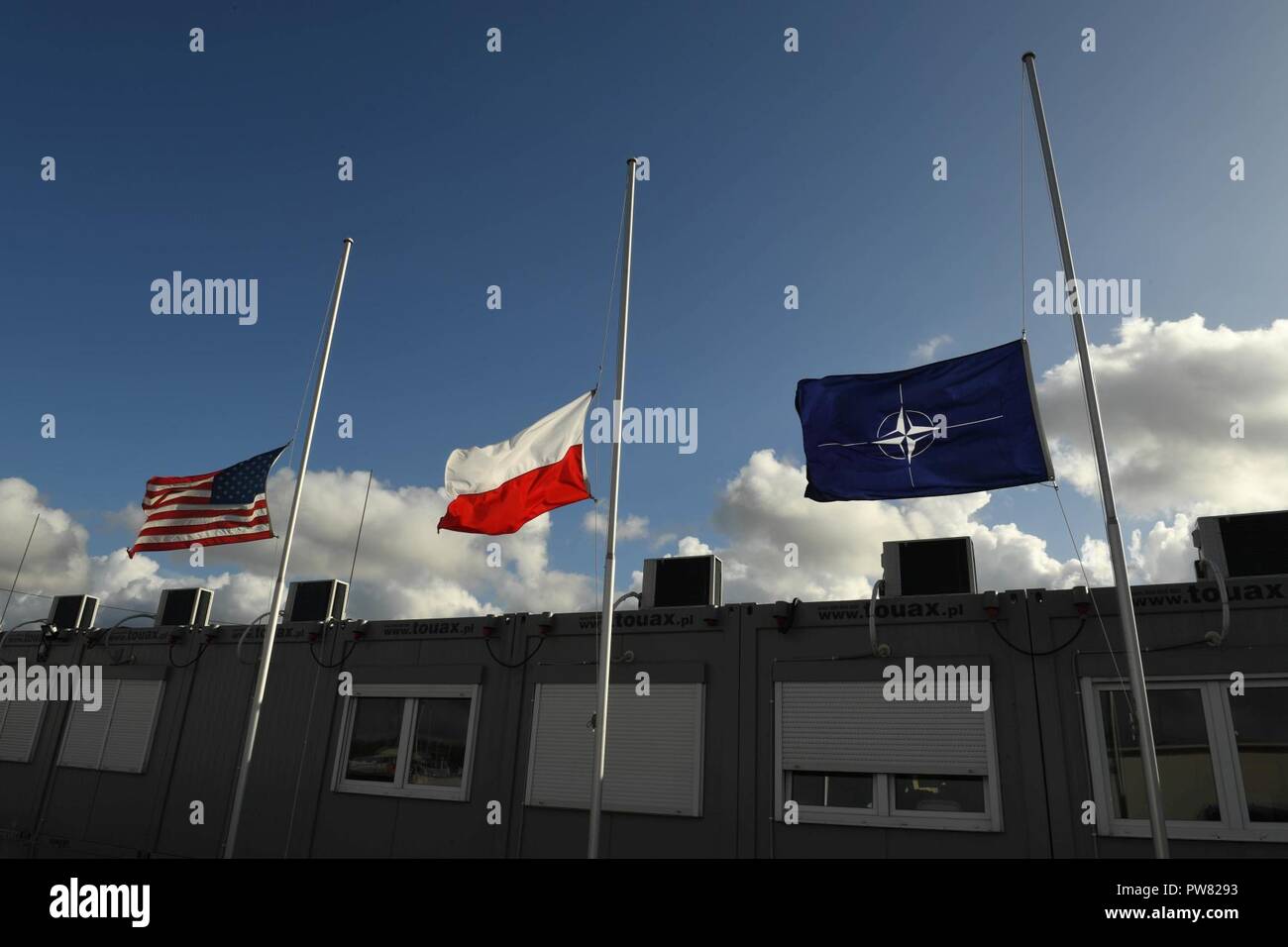 NAVAL SUPPORT FACILITY REDZIKOWO, Poland (Oct. 3, 2017). Naval Support Facility (NSF) Redzikowo flies the United States flag, the flag of Poland, and the flag of the North Atlantic Treaty Organization (NATO) at half-staff until sunset on Oct. 6 as a remark of respect for the victims of a mass shooting in Las Vegas, Nevada, Oct. 1. NSF Redzikowo is the Navy’s newest installation, and the first U.S. installation in Poland. Its operations enable the responsiveness of U.S. and allied forces in support of Navy Region Europe, Africa, Southwest Asia’s (EURAFSWA) mission to provide services to the Fle Stock Photo
