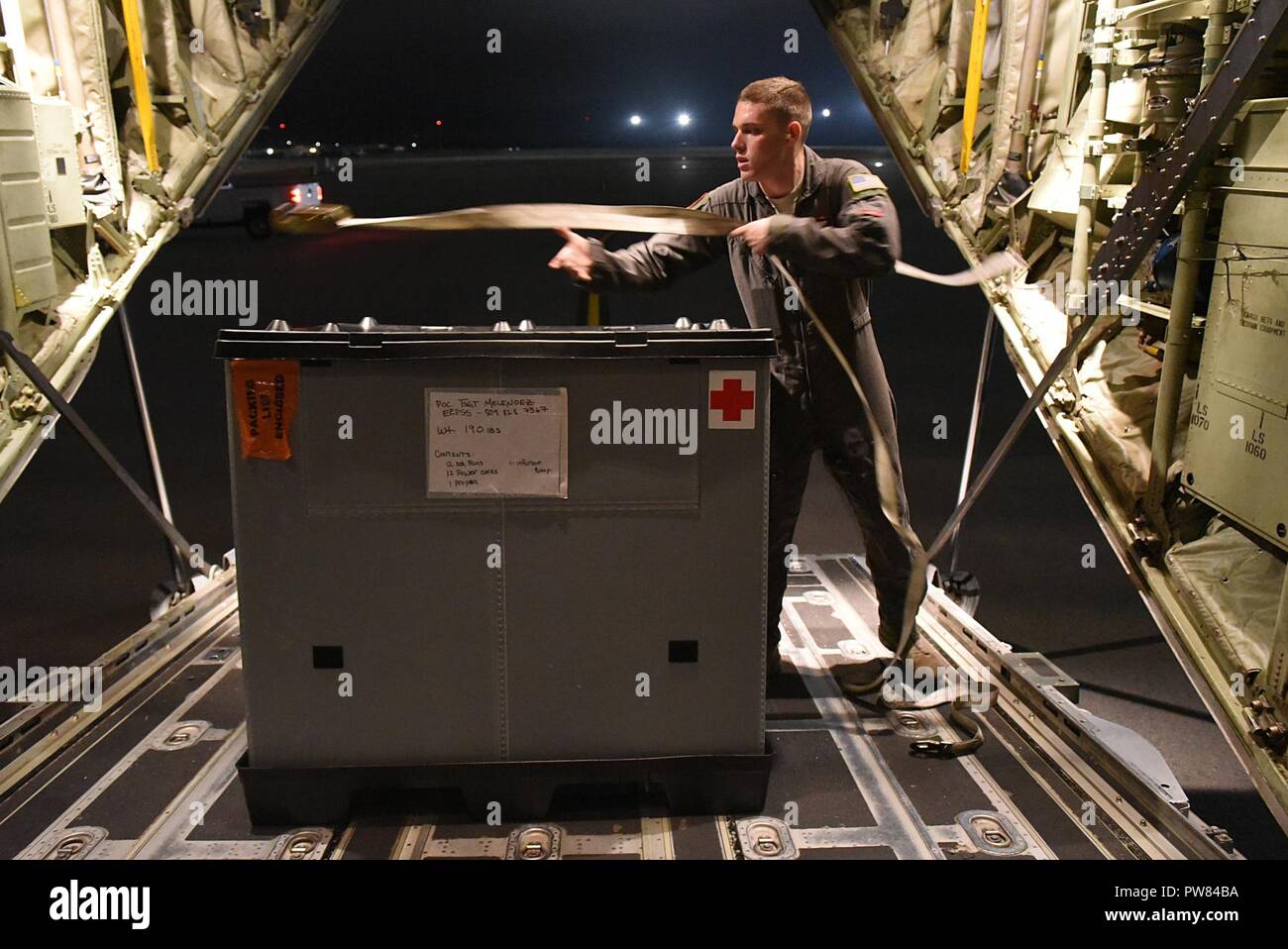 Airman 1st Class Micah Fernandez, 41st Airlift Squadron loadmaster, secures an En Route Patient Staging System on a C-130J stationed at Little Rock Air Force Base, Ark., Oct. 1, 2017, at MacDill Air Force Base, Fla. Members of the 41st AS and the 61st AS flew multiple missions to Puerto Rico and the U.S. Virgin Islands to transport patients and passengers as well as food, water and medicine. Stock Photo