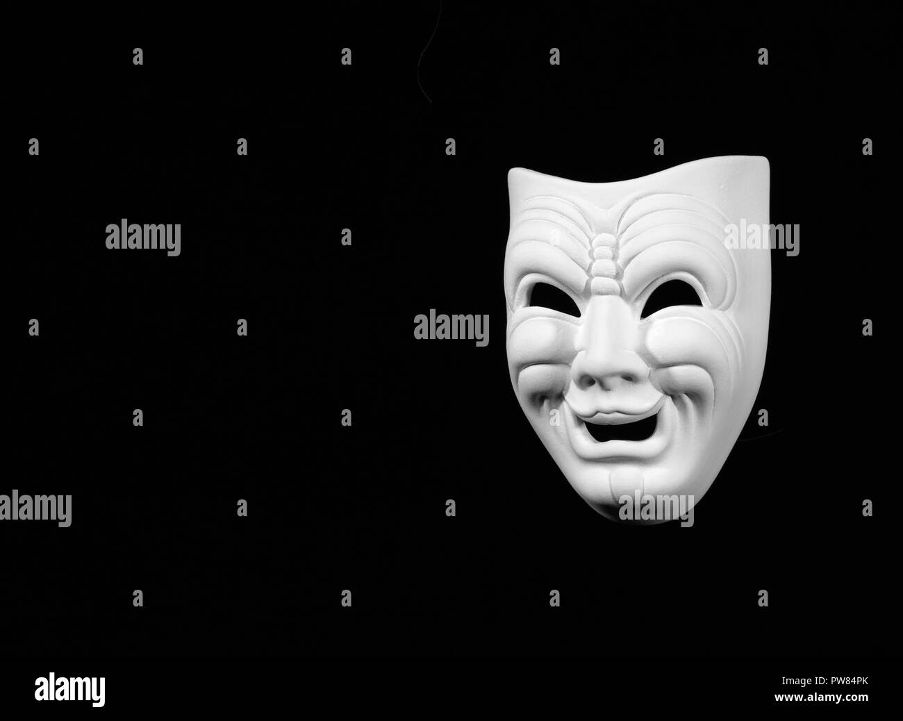 theatre mask expresing the comedy, white mask on black background with free space for text Stock Photo