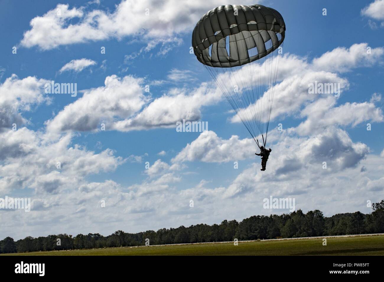 A member of the 820th Base Defense Group (BDG) descends during a static-line jump, Oct. 3, 2017, at the Lee Fulp drop zone in Tifton, Ga. The 820th Combat Operations Squadron’s four-person shop of parachute riggers are responsible for ensuring every 820th BDG parachute is serviceable, while also ensuring ground safety at the drop zone. The team has packed and inspected more than 490 parachutes in 2017. Stock Photo