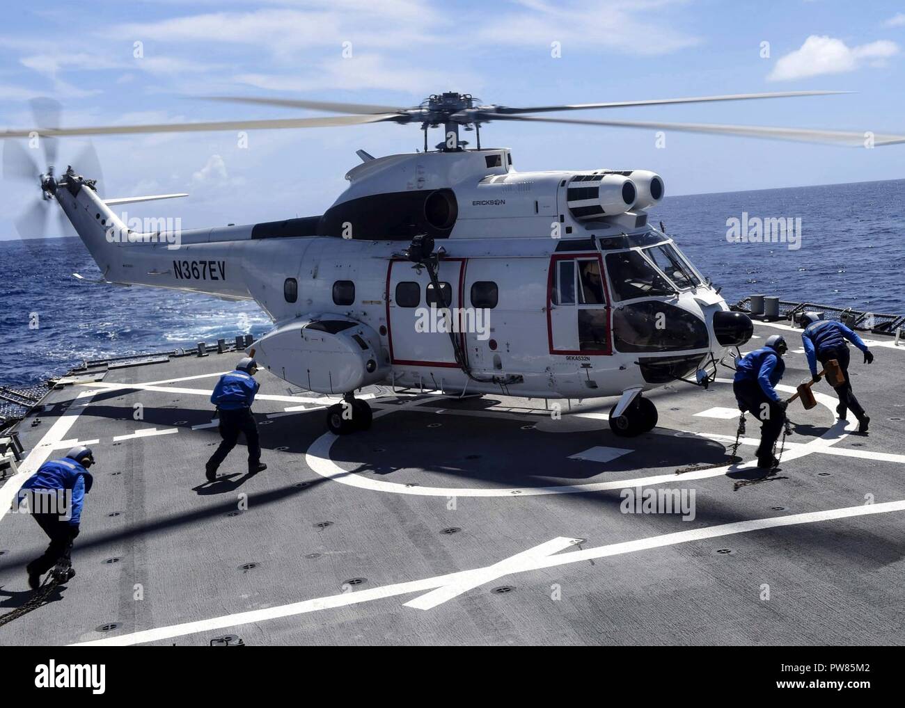 WATERS NEAR GUAM (Sept. 26, 2017) Sailors run out to chalk and chain an SA-330J Puma helicopter, assigned to USNS Amelia Earhart (T-AKE 6) on the flight deck of the Arleigh Burke-class guided-missile destroyer USS Benfold (DDG 65). Benfold is on patrol in the U.S. 7th Fleet area of operations in support of security and stability in the Indo-Asia-Pacific. Stock Photo