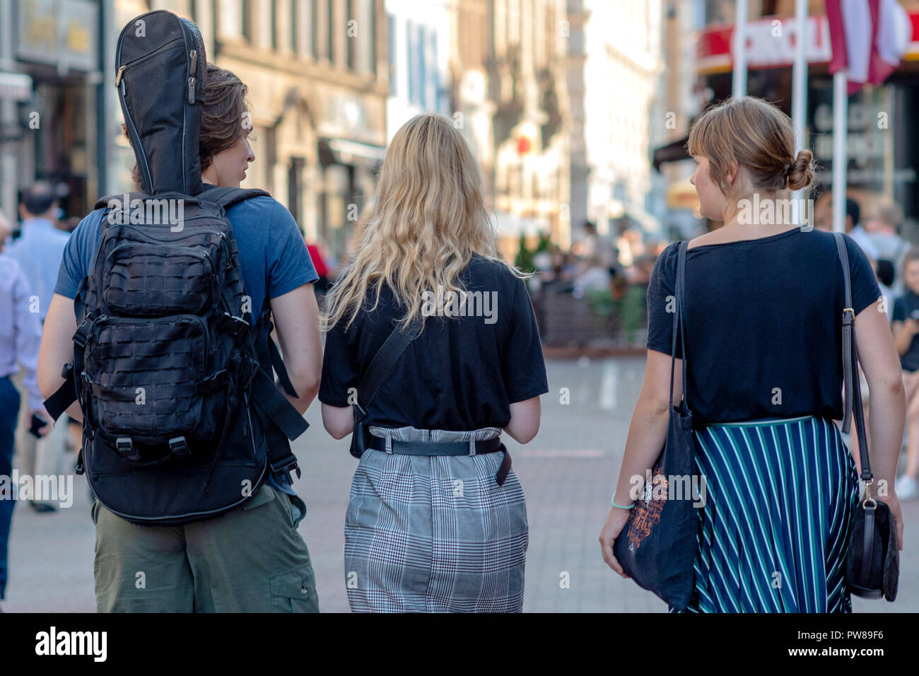 RIGA, LATVIA - JULY 26, 2018: A man and two women walk along the streets of the city. View from the back. Stock Photo