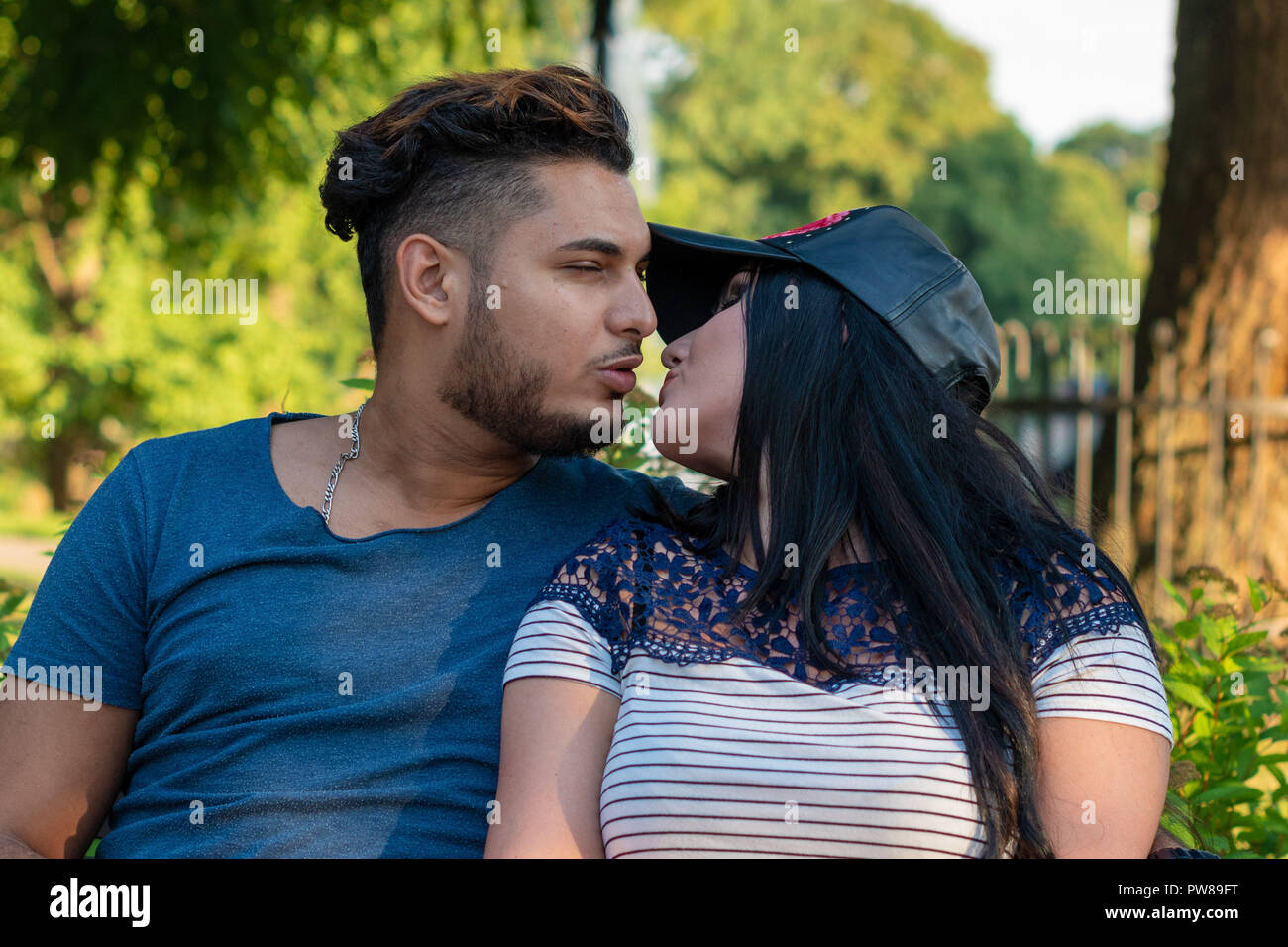 RIGA, LATVIA - JULY 26, 2018: Young couple in love kissing in the park. Stock Photo