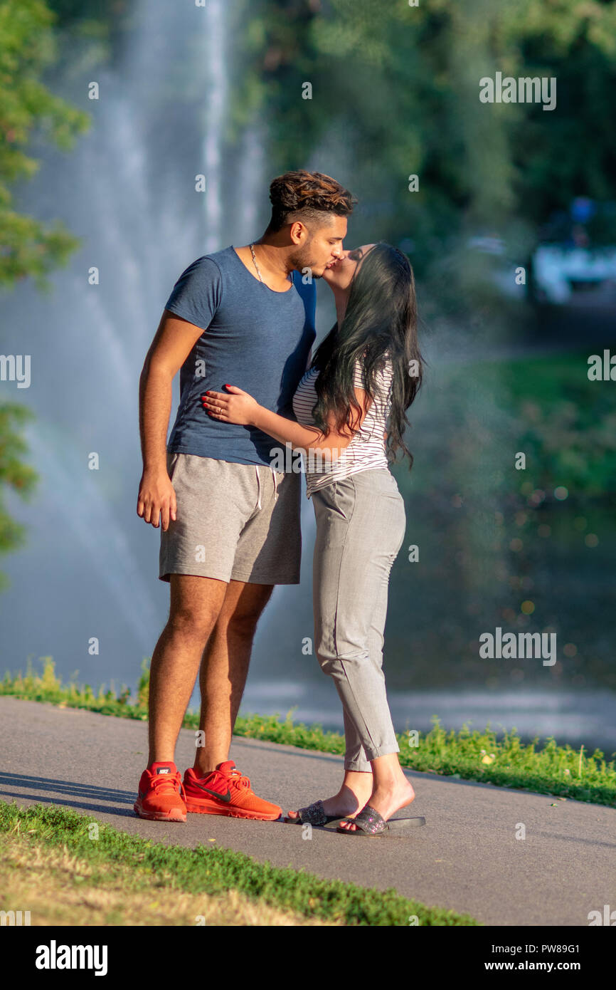 RIGA, LATVIA - JULY 26, 2018: Young couple in love kissing in the park. Stock Photo