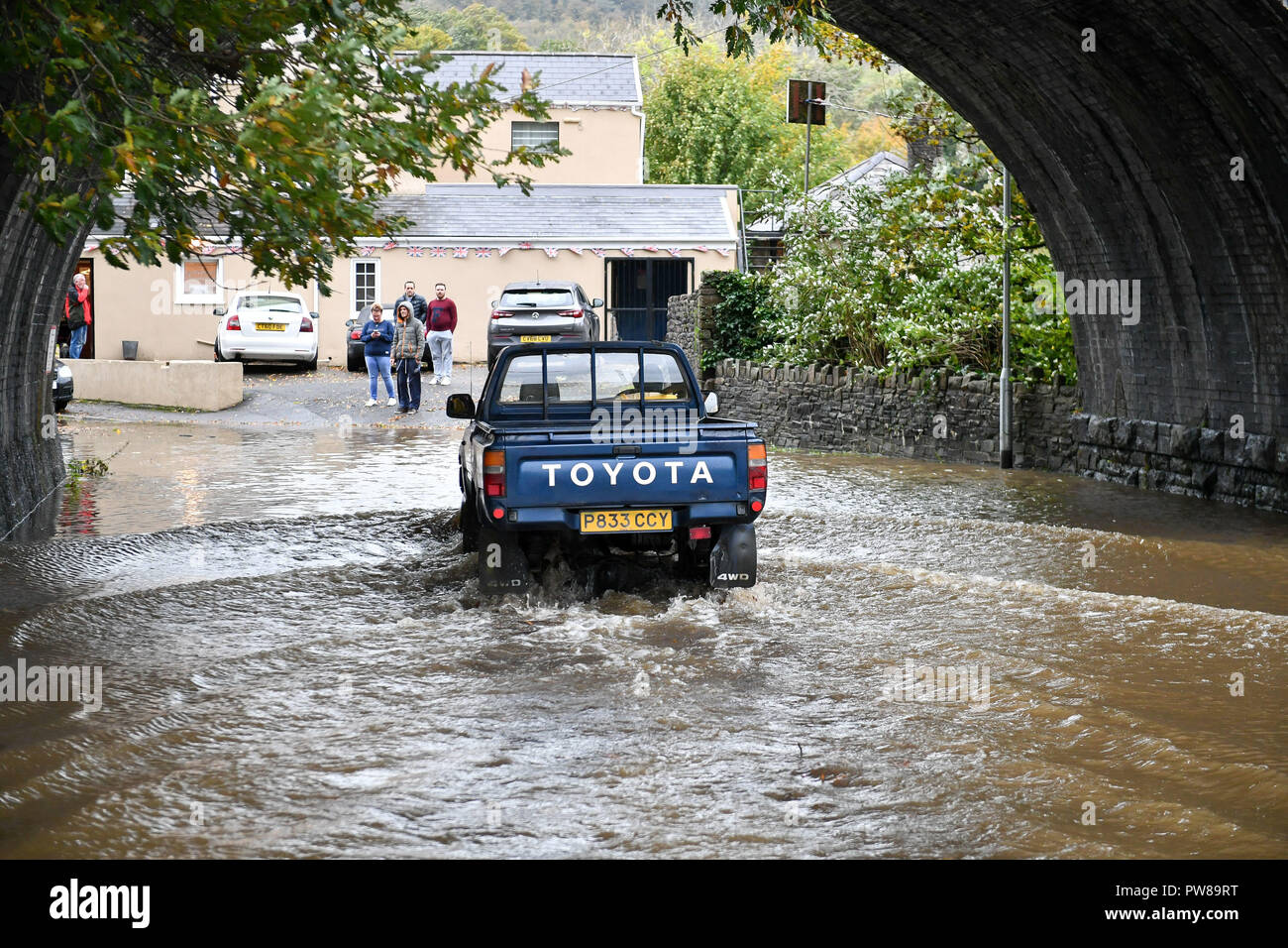 A 4x4 vehicle drives through flood water on the road to the Aberdulais Royal British Legion club in Aberdulais, Neath, South Wales, where an amber weather warning is in force across the region as heavy rain is causing flooding. Stock Photo