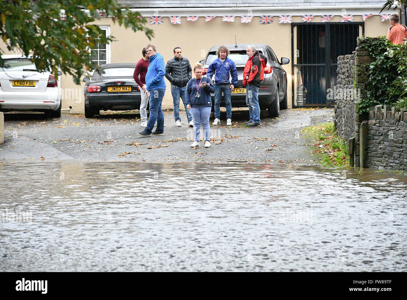 People check floodwater blocking the road to the Aberdulais Royal British Legion club in Aberdulais, Neath, South Wales, where an amber weather warning is in force across the region as heavy rain is causing flooding. Stock Photo
