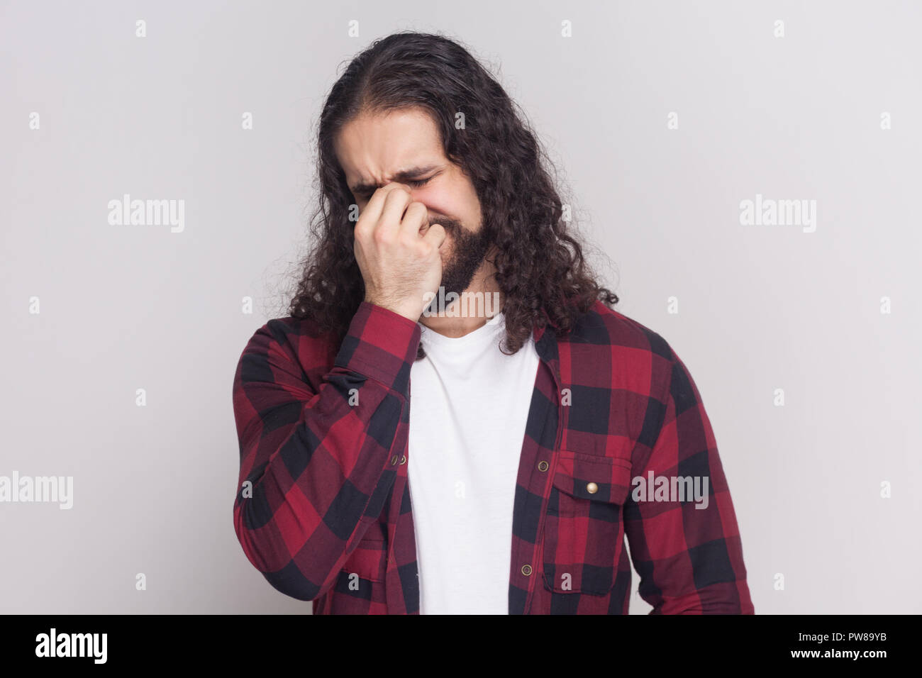 Portrait of sad crying man with beard and black long curly hair in casual style, checkered red shirt standing with depressed face, sorrow and crying.  Stock Photo