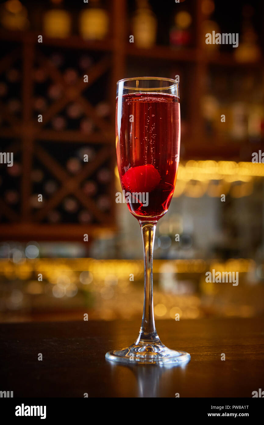 Red Cocktail in Champagne Glass near in the Bar with Amazing Blurred Background. Stock Photo