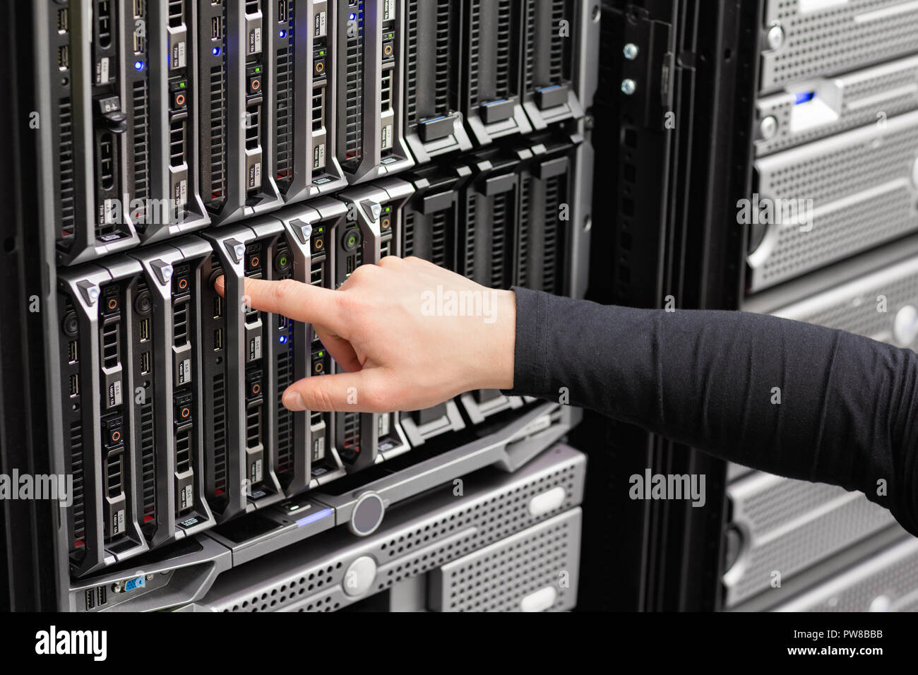 Male IT Engineer Installing Blade Server In SAN At Datacenter Stock Photo