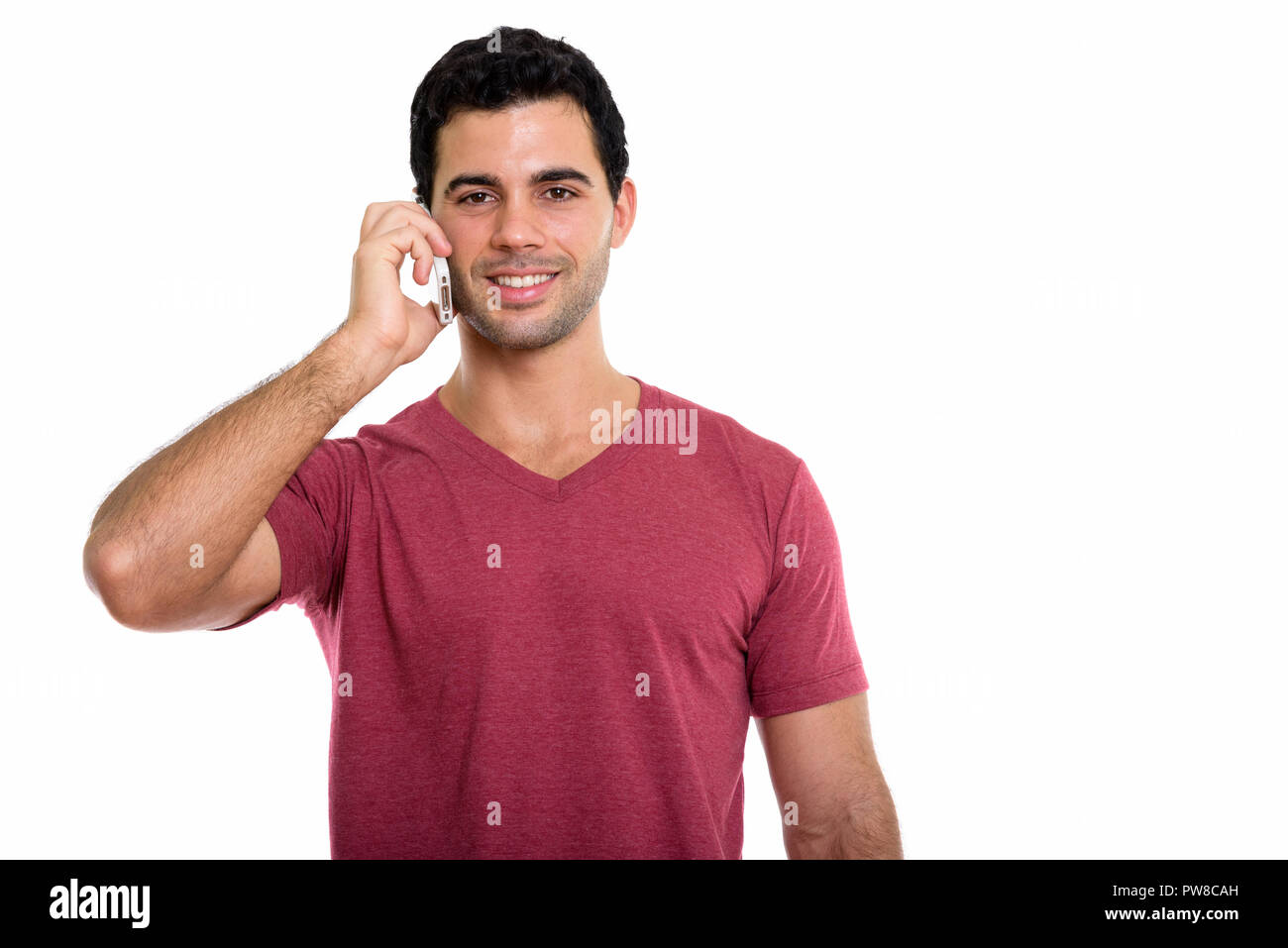 Studio shot of young happy Hispanic man smiling while talking on Stock Photo