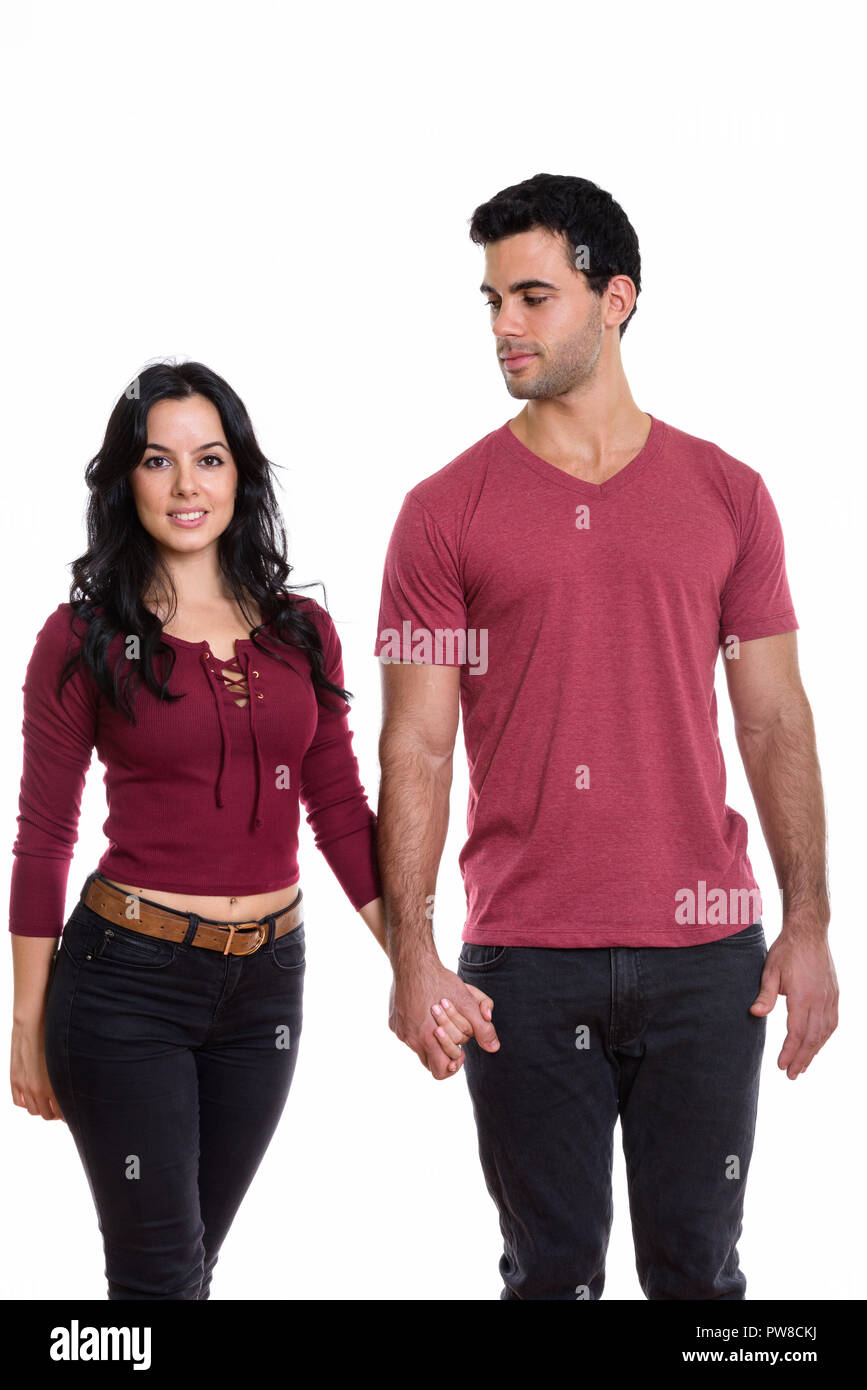 Studio shot of young happy couple smiling and holding hands toge Stock Photo
