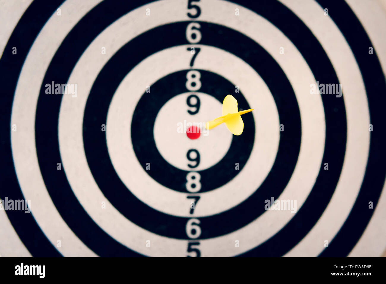 Dart arrow hitting the target of dartboard on white background. Hitting the bull's eye. Clear aim. Well-aimed dart throwing. A marksman's true hit. A Stock Photo