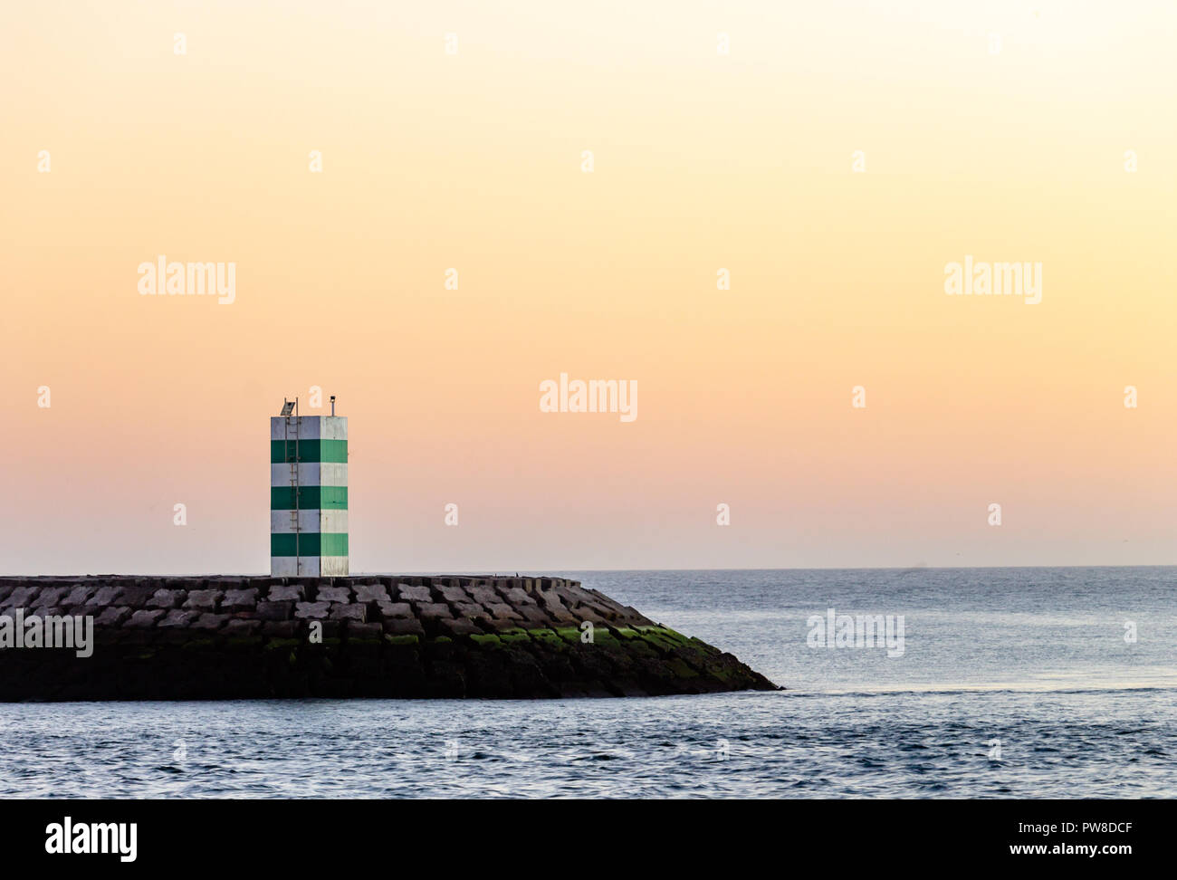 Panorama of a lighthouse with green stripes after sunset. Stock Photo