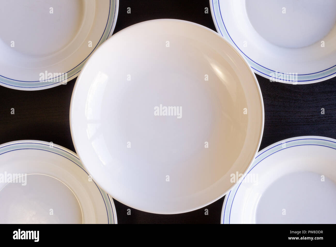 A black wooden background with five blue and white empty plates. Stock Photo