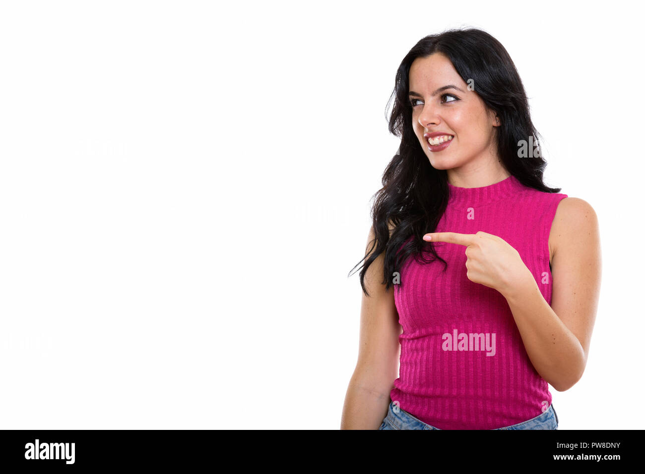 Studio shot of young happy Spanish woman smiling while pointing  Stock Photo