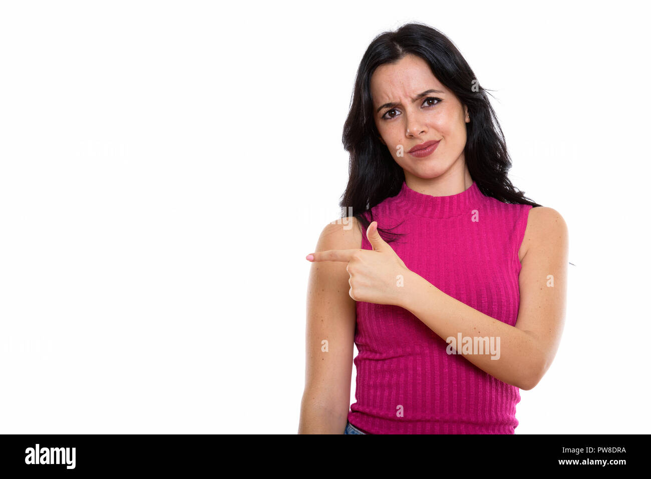 Studio shot of young beautiful Spanish woman pointing at side lo Stock Photo