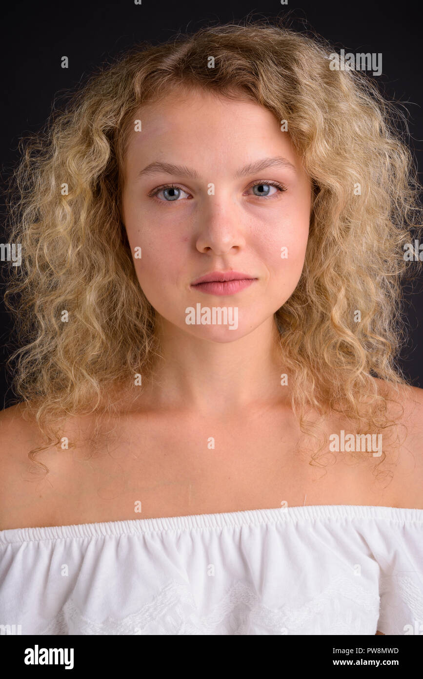 Young beautiful woman with blond curly hair against gray backgro Stock Photo