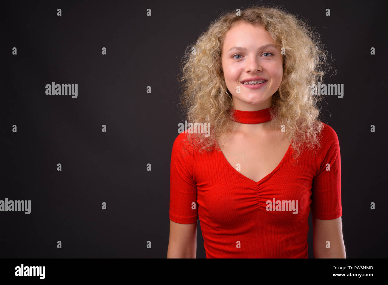 Young beautiful woman with blond curly hair against gray backgro Stock Photo