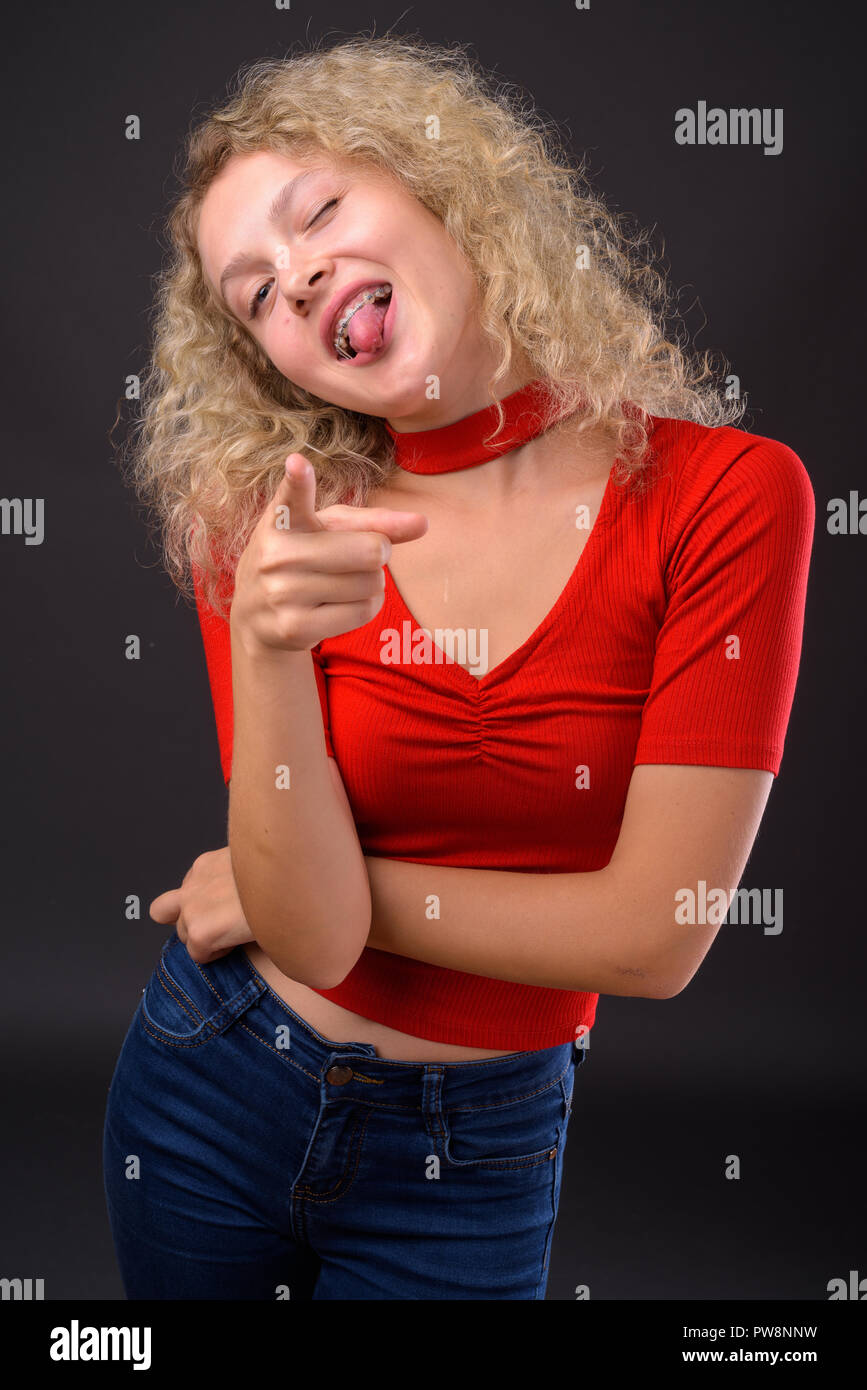 Young beautiful woman with blond curly hair against gray backgro Stock Photo