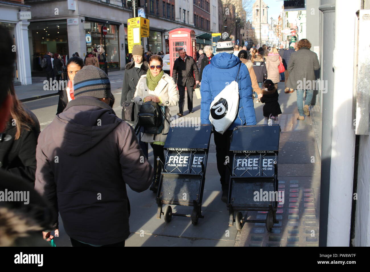 LONDON, UK - February 16, 2018: Newspaper boy dragging newspapers racks on the street. Stock Photo