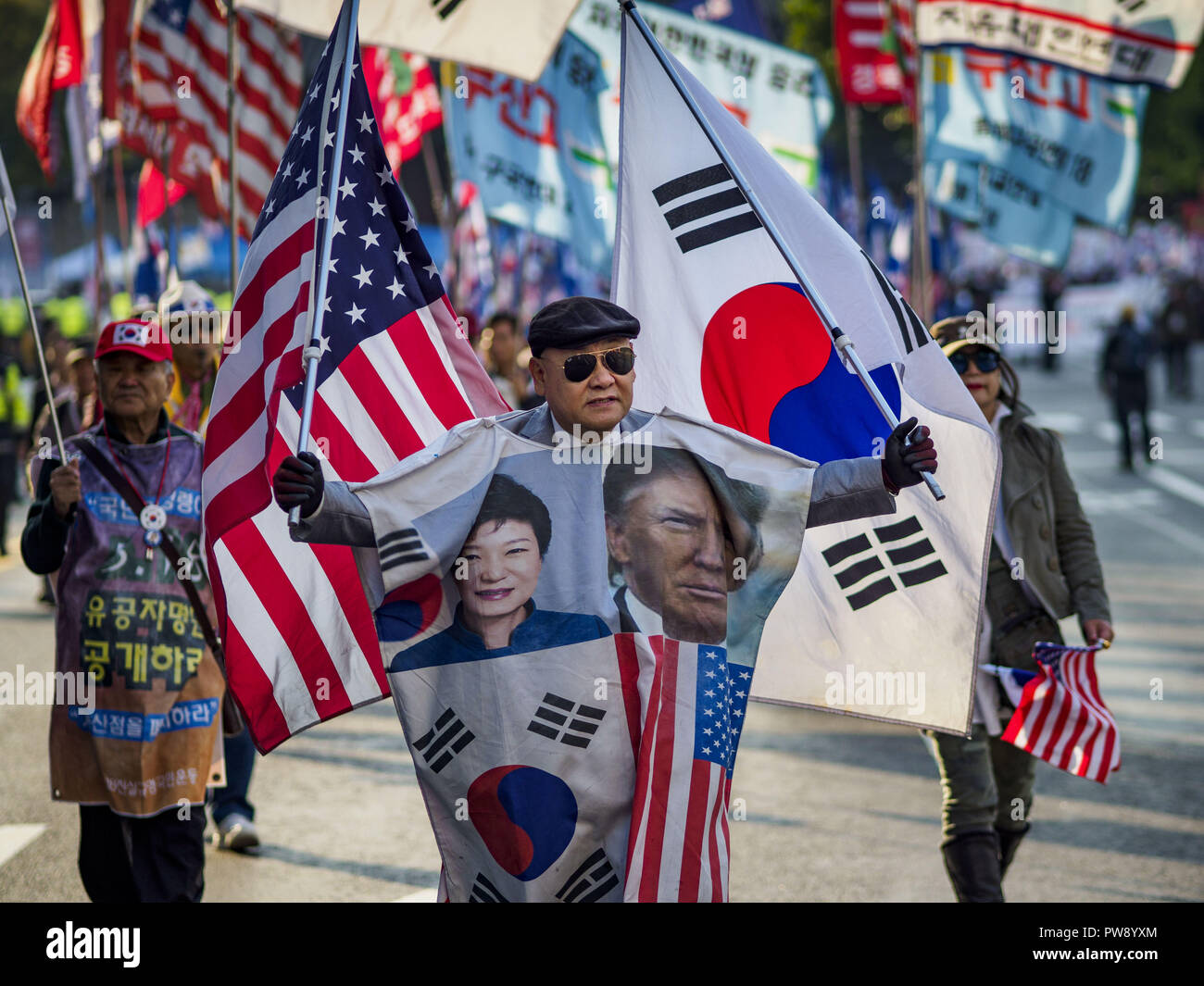Seoul, South Korea. 13th Oct, 2018. A man wearing a poncho decorated with  portraits of ousted South Korean President Park and US President Trump  carries the US and South Korean flags on