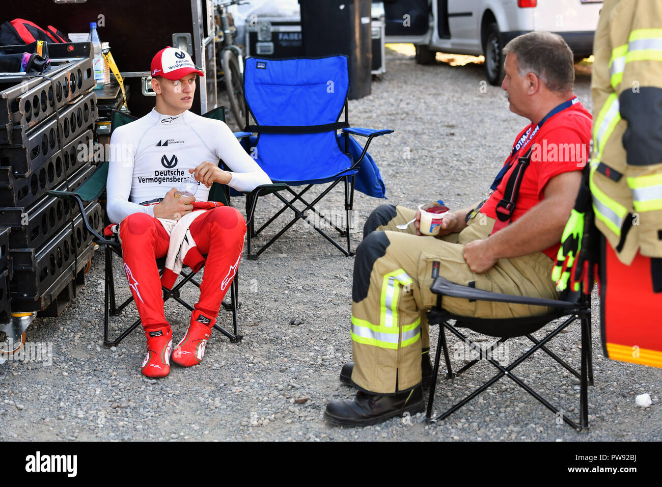 Hockenheim, Deutschland. 13th Oct, 2018. Mick SCHUMACHER, (GER, PREMA Theodore Racing) sits next to a firefighter in a camping chair and talks to him. Fia Formula 3 European Championships, Formula 3, at the Hockenheimring on 13.10.2018. | usage worldwide Credit: dpa/Alamy Live News Stock Photo