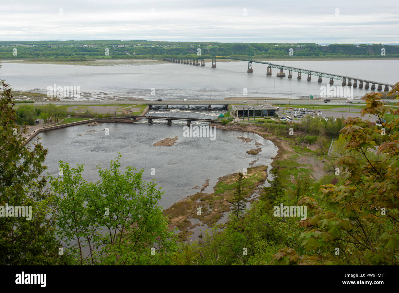 Tributary to St. Lawrence River, the Montmorency River joins it downstream of Montmorency Falls. Île d'Orléans and a suspension bridge in the back. Stock Photo