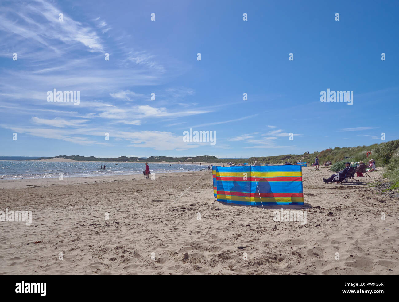 Holidaymakers enjoying the warm temperatures and clean Sand of Beadnell Bay in Northumberland, England, UK Stock Photo