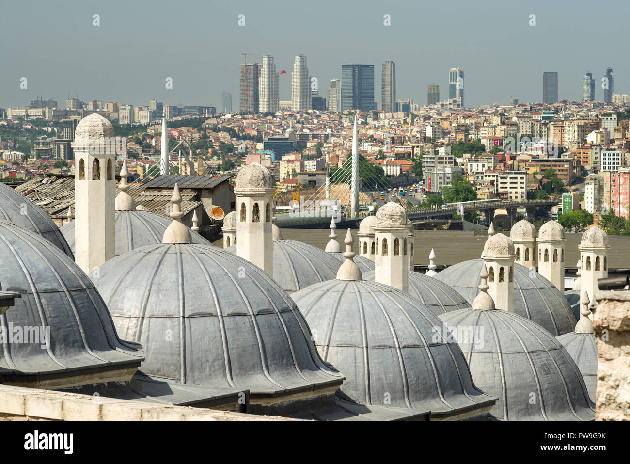 Stone chimneys of domed buildings with Golden Horn Metro Bridge in background, Istanbul, Turkey Stock Photo