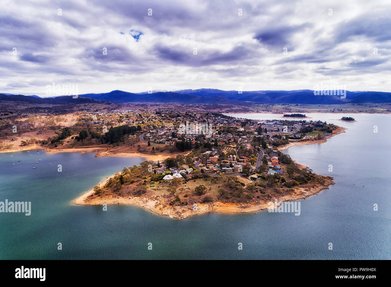 Jindabyne town on shores of Jindabyne lake in winter with distant mountain peaks of Snowy