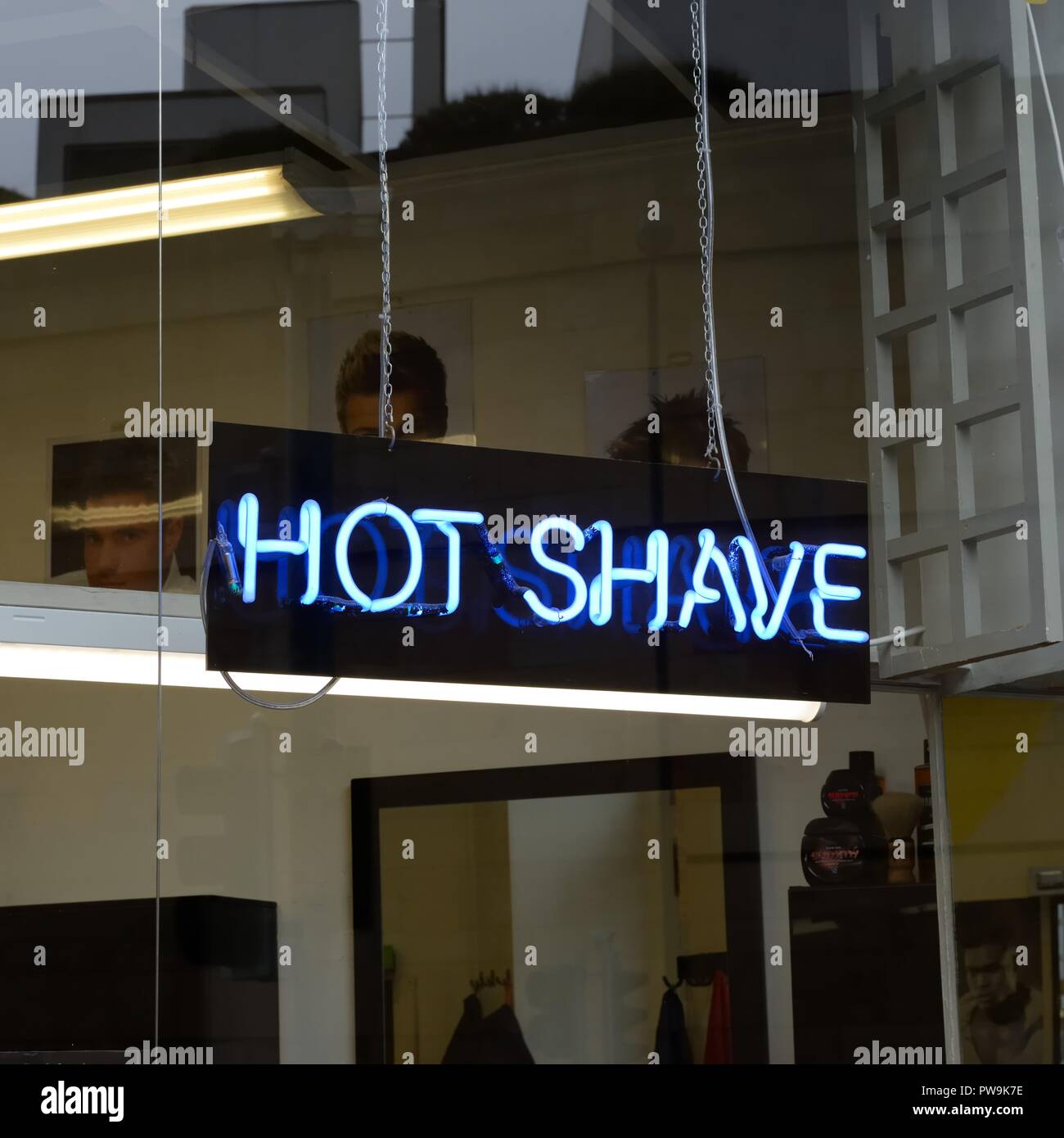 A neon tube sign in a barber shop window advertising a 'Hot Shave' in the UK, Europe Stock Photo