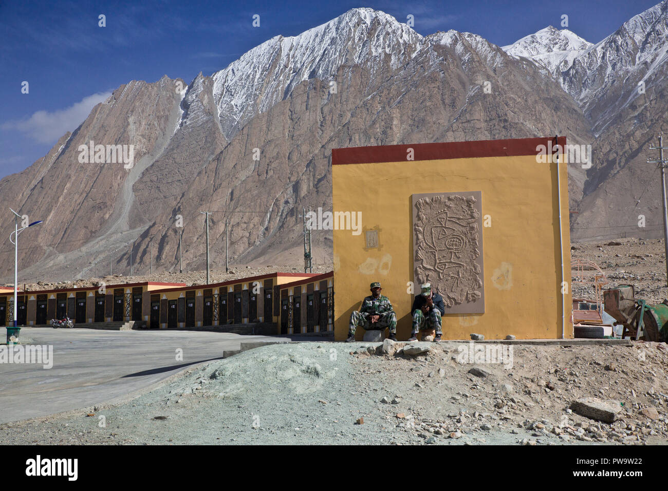 Two men sitting beneath the mountains at White Sands Lake, China Stock