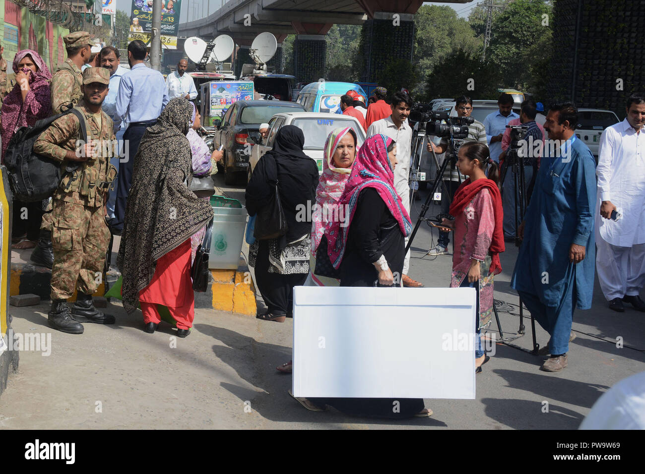 Election Commission of Pakistan's (ECP) staff is bringing ballot boxes and other items to a polling station established at Government Islamia High School ahead of the by-elections under the supervision of Pak Army personnel in Lahore on October 13, 2018. Pak Army personnel and Pakistani election presiding officers carry election materials for a by-election after receiving from the distributing point in Lahore, Over 100 candidates are contesting for 35 National Assembly and provincial assembly seats in the by-election scheduled for October 14. (Photo by Rana Sajid Hussain/Pacific Press) Stock Photo