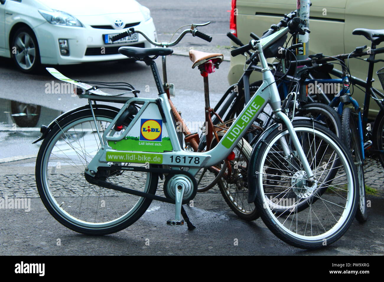 Lidl Bike - Berlin Bike Sharing Scheme - Public cycling - with other bikes and car in background Stock Photo
