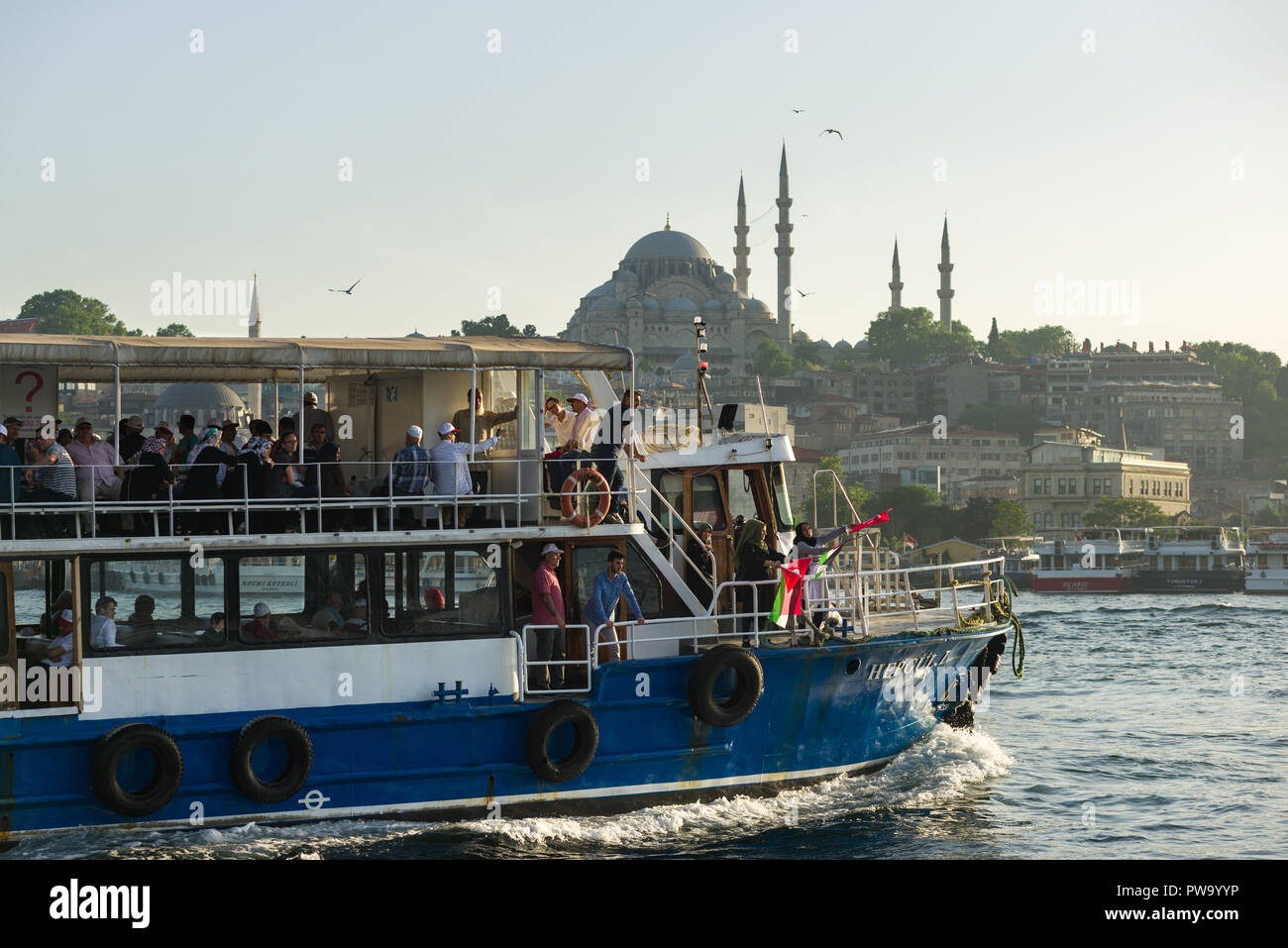 A ferry with passengers on sails on the Bosphorus with Suleymaniye mosque in the background, Istanbul, Turkey Stock Photo