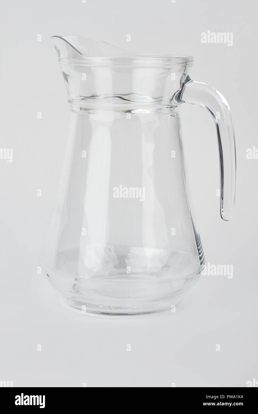 Empty glass jug isolated. Glass jug with handle on light background. Glass ware for milk Stock